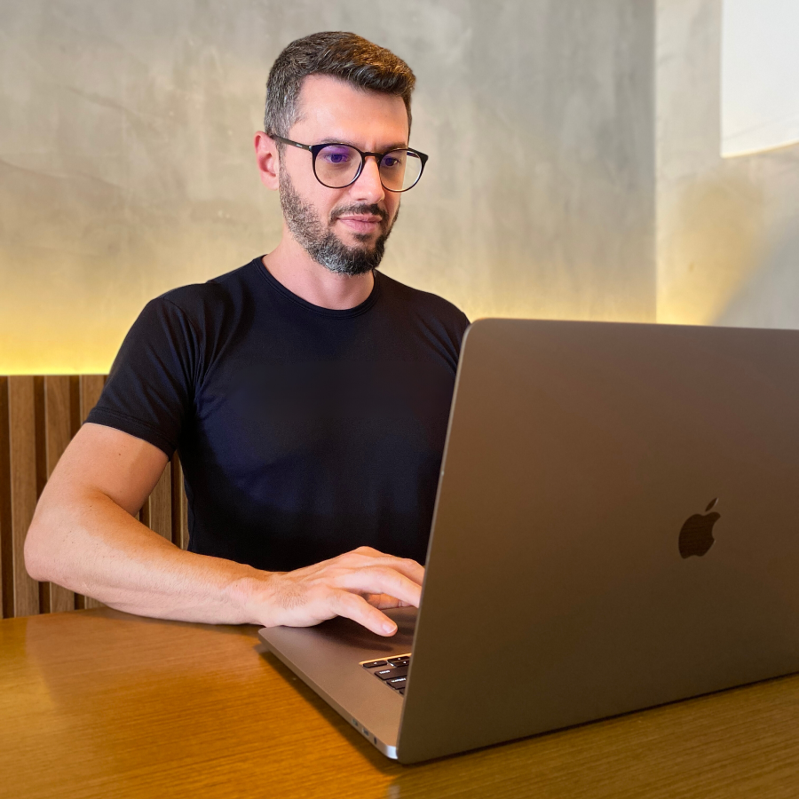 Professor Tiago Segato usando seu computador em um ambiente aconchegante
